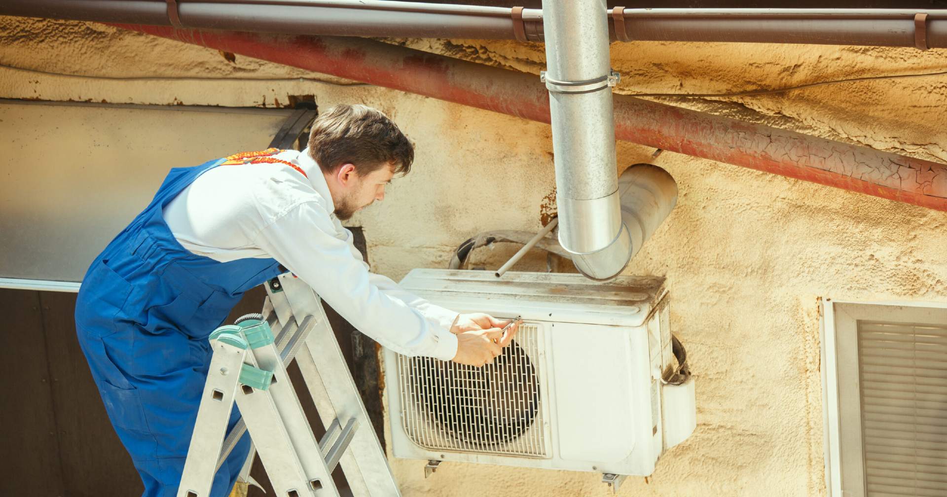 HVAC technician working on a capacitor part for condensing unit. Male worker or repairman in uniform repairing and adjusting conditioning system, diagnosting and looking for technical issues.